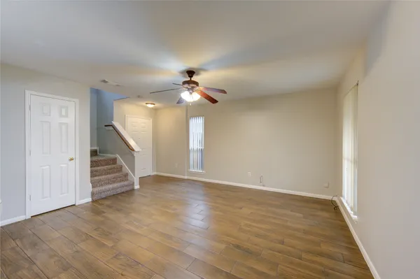 a view of an empty room with wooden floor and stairs