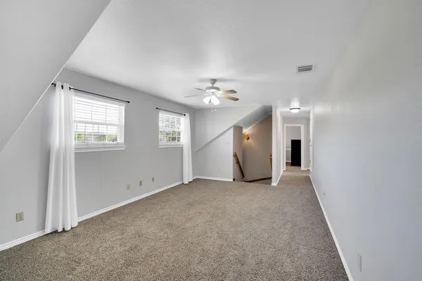 an empty room with a ceiling fan and a window