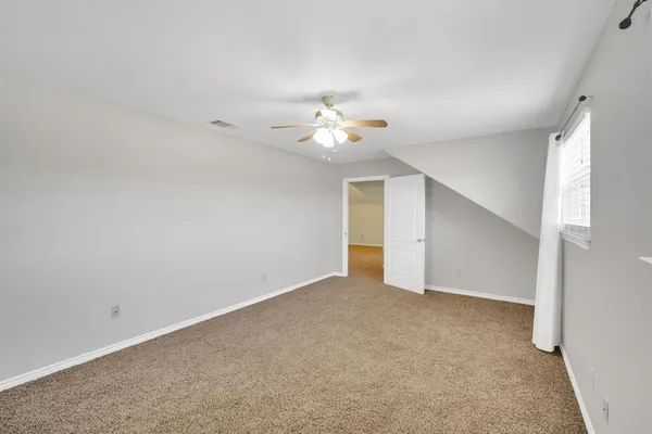 an empty room with windows and fan