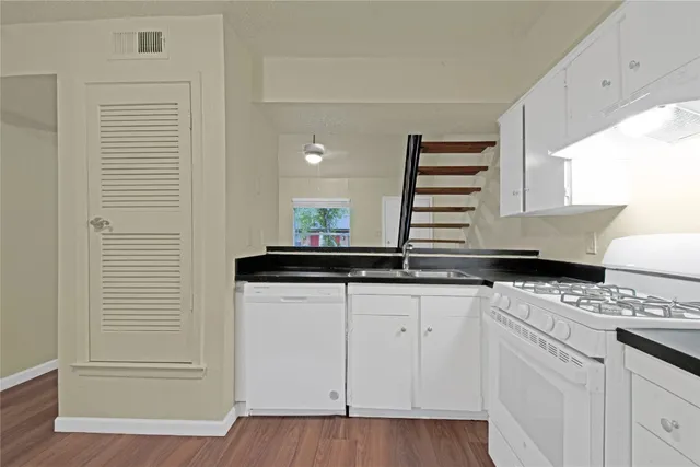 a kitchen with granite countertop white cabinets and white appliances