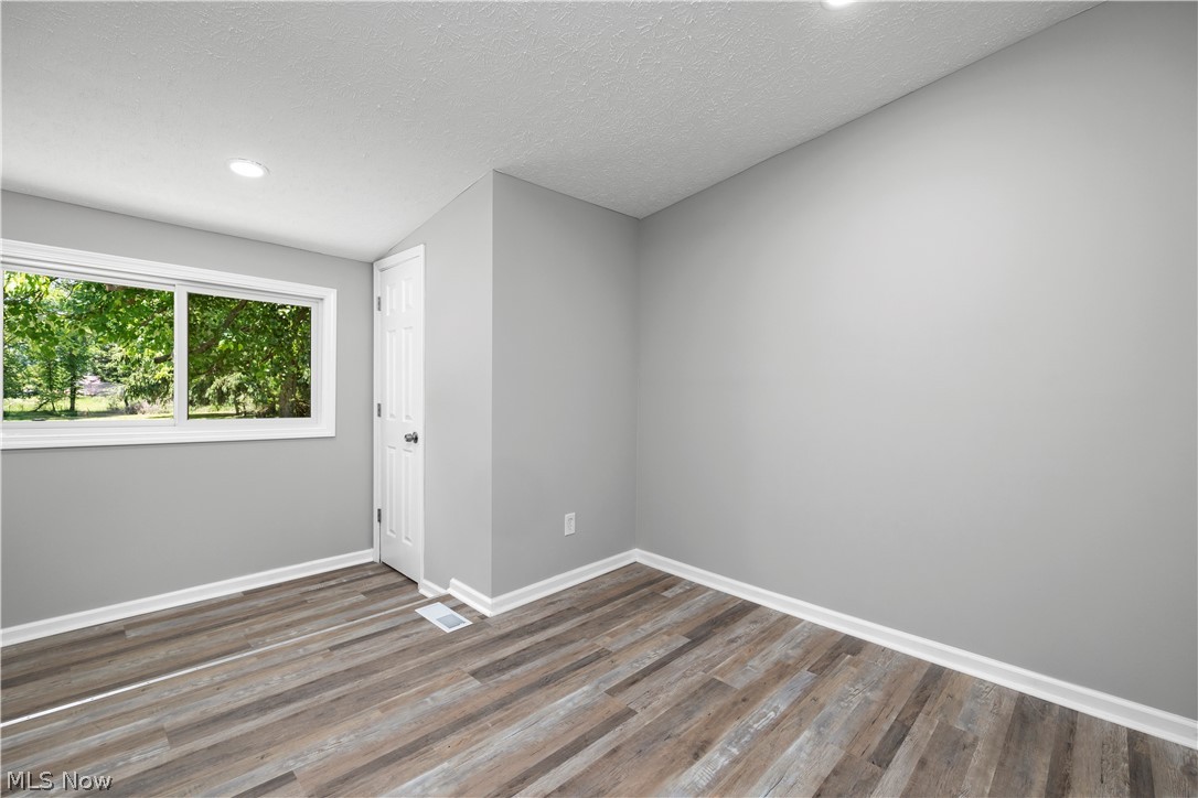 7030 Pearl Road Cleveland, OH 44130 - Photo 11 of 34 Unfurnished room with a textured ceiling, lofted ceiling, and dark hardwood / wood-style flooring