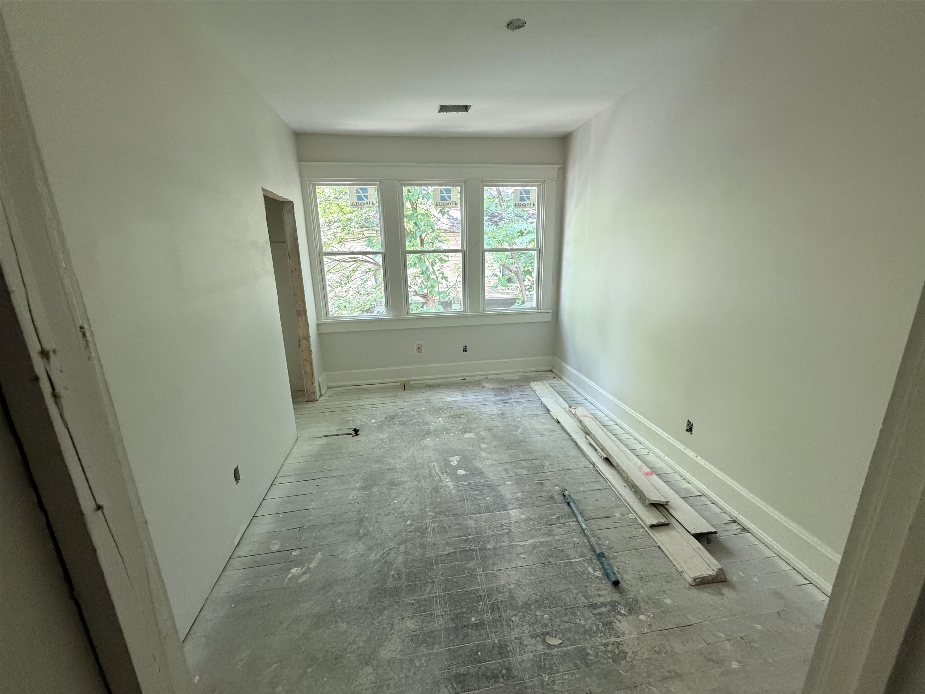 961 Meda Street Memphis, TN 38104 - Photo 12 of 27 Unfinished interior space featuring a bank of three double-hung windows, a partially finished doorway, baseboard trim, and smooth wall finishes