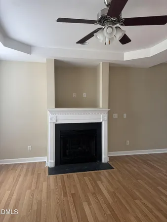 a view of an empty room with wooden floor fireplace and a window
