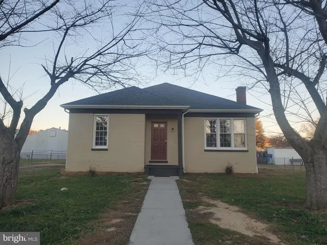 a front view of a house with a yard and trees