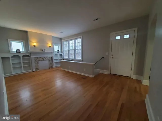 an empty room with wooden floor cabinet and windows