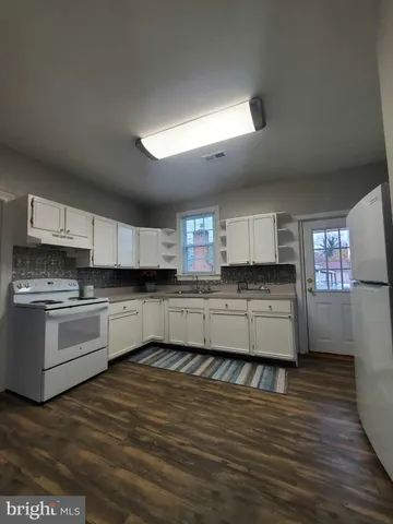 a kitchen with stainless steel appliances kitchen island granite countertop a stove a sink and white cabinets