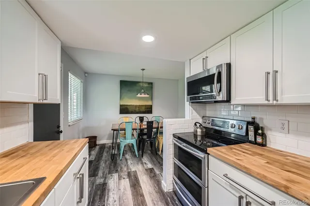 a kitchen with stainless steel appliances kitchen island granite countertop a stove top oven a sink a counter space and cabinets