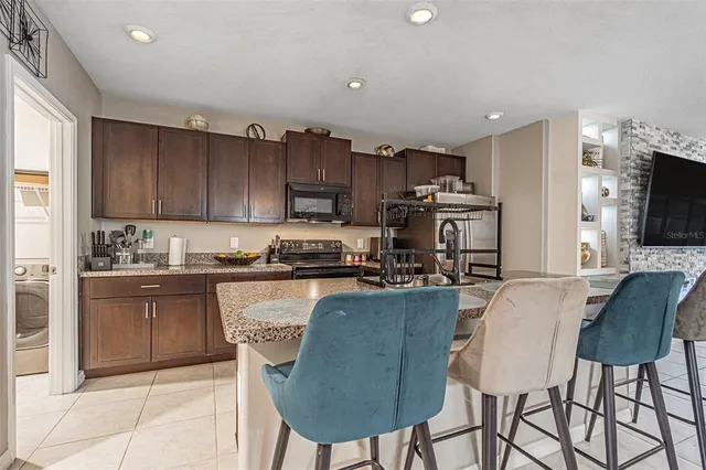 a kitchen with kitchen island granite countertop a stove top oven a sink a dining table and chairs