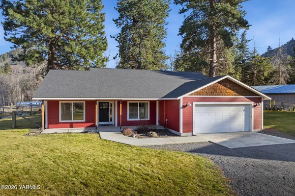 a front view of house with yard and trees in the background