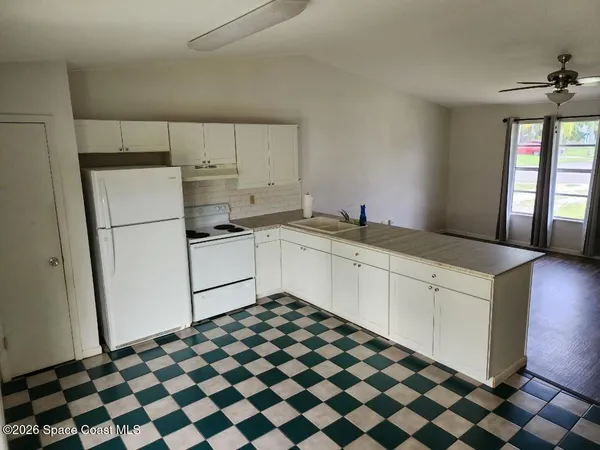 a kitchen with a checkered floor and white cabinets