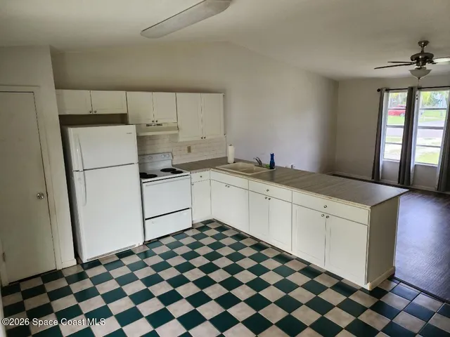 a kitchen with a checkered floor and white cabinets