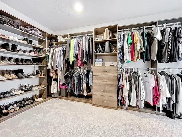 a view of walk in closet with clothes and shoes