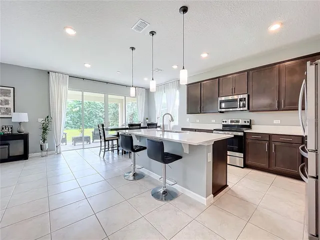 a kitchen with stainless steel appliances kitchen island granite countertop a stove a sink a counter top space cabinets and a view of living room