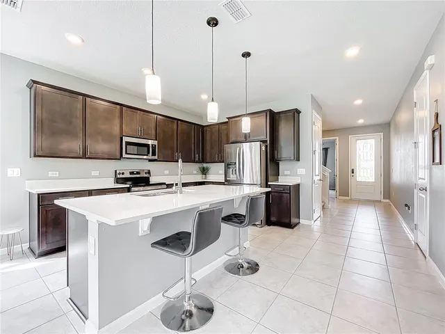 a kitchen with stainless steel appliances a stove a sink a microwave a refrigerator and cabinets