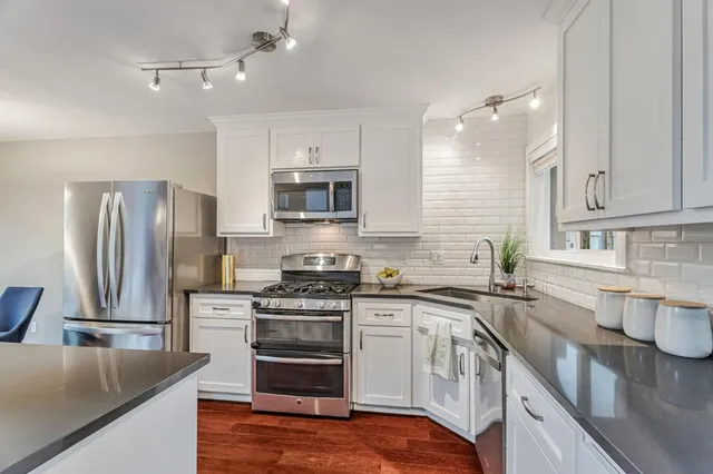 a kitchen with stainless steel appliances granite countertop a sink stove and refrigerator