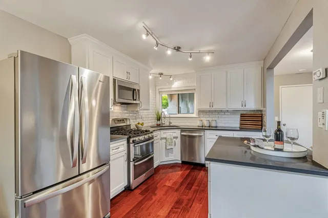 a kitchen with stainless steel appliances granite countertop a refrigerator a stove top oven a sink and dishwasher