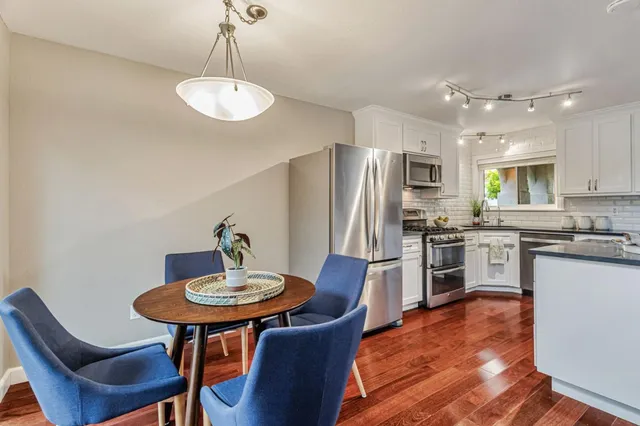 a kitchen with stainless steel appliances granite countertop a dining table chairs refrigerator and sink