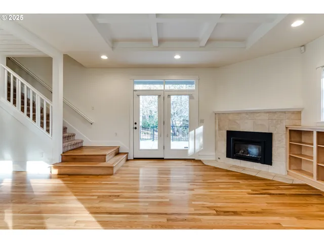 a view of an empty room with wooden floor fireplace and a window
