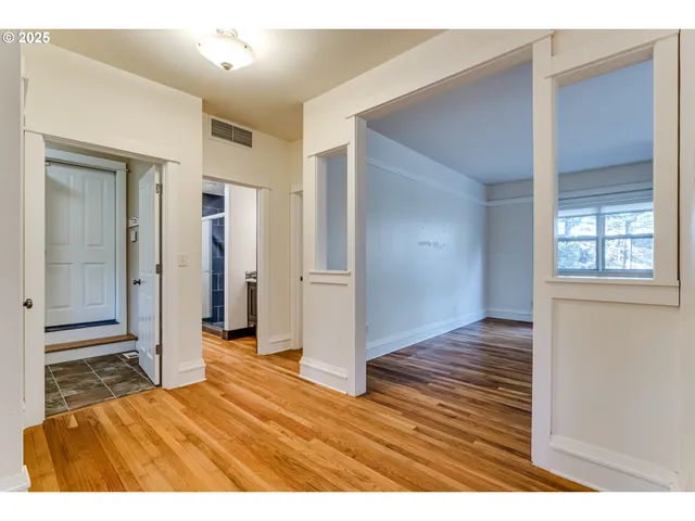a view of an empty room with wooden floor and a window