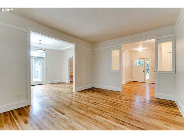 a view of an empty room with window and wooden floor
