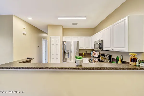 a kitchen with stainless steel appliances granite countertop a sink a stove and a refrigerator with wooden floor
