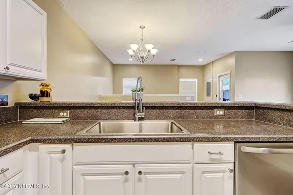 a kitchen with granite countertop a sink flowers and cabinets