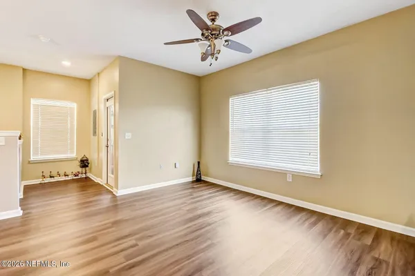 a view of an empty room with wooden floor and a window