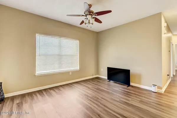 a view of an empty room with window and wooden floor