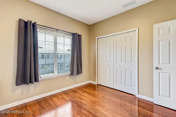 a view of an empty room with wooden floor and a window
