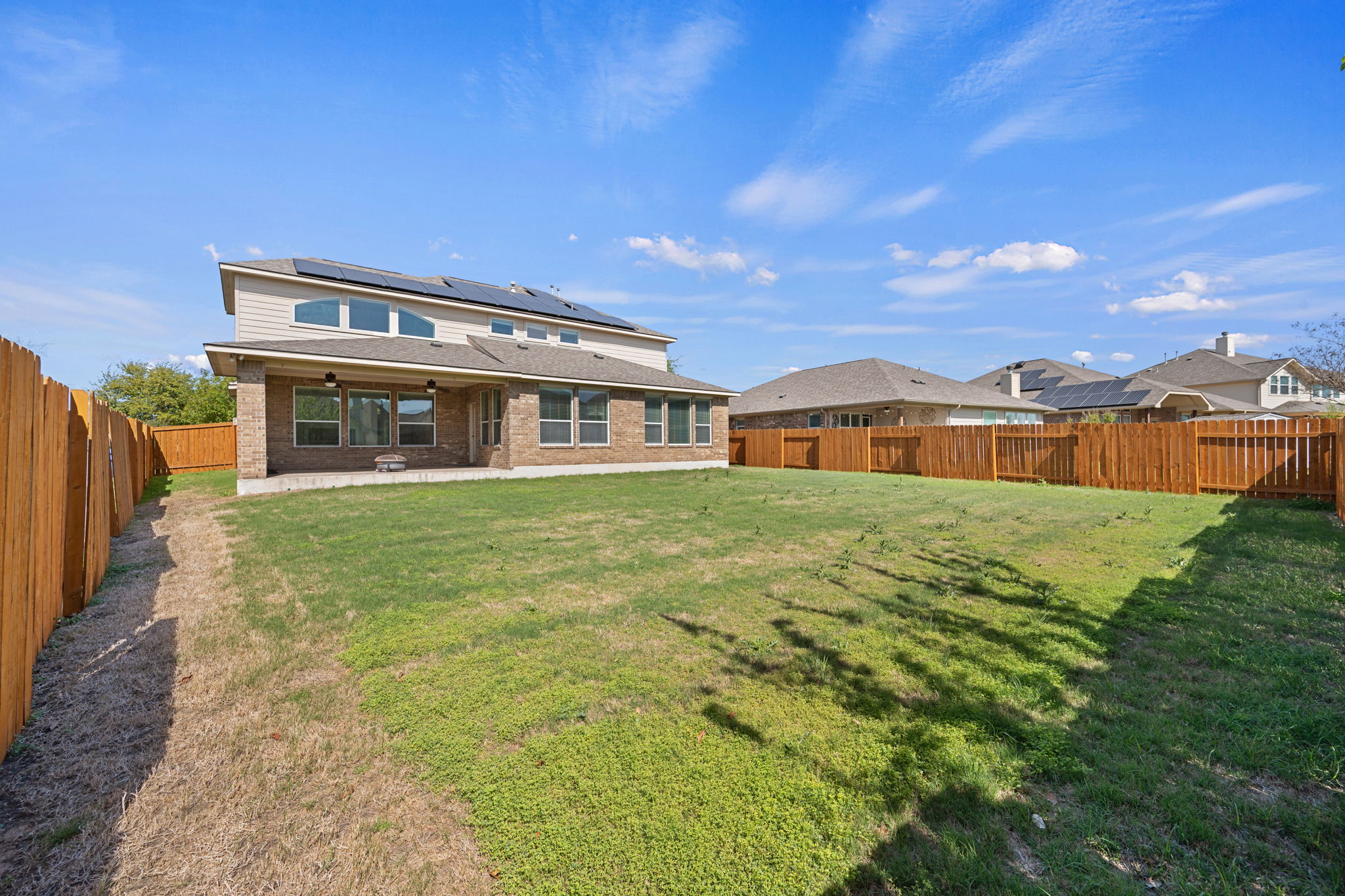 3904 Brean Down Road Pflugerville, TX 78660 - Photo 34 of 40 Back of property with roof mounted solar panels, a patio, brick siding, ceiling fan, and a fenced backyard