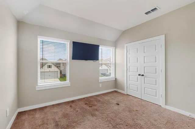 a view of an empty room with a window and a kitchen