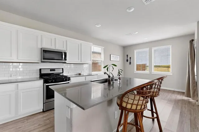 a kitchen with sink a microwave and cabinets