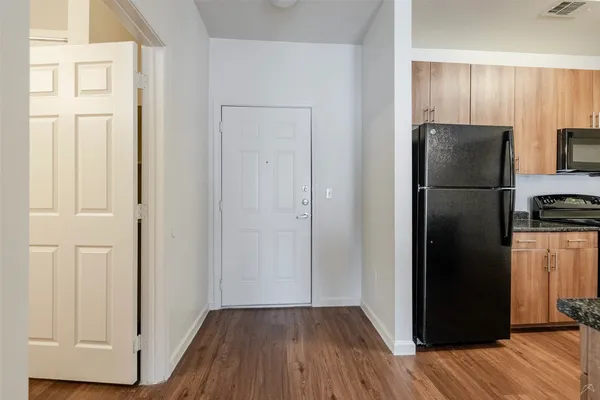 a view of a kitchen with refrigerator and wooden floor