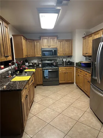 a kitchen with stainless steel appliances granite countertop a stove top oven a sink dishwasher and a refrigerator