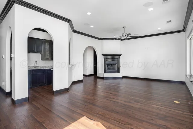 a view of empty room with wooden floor and kitchen