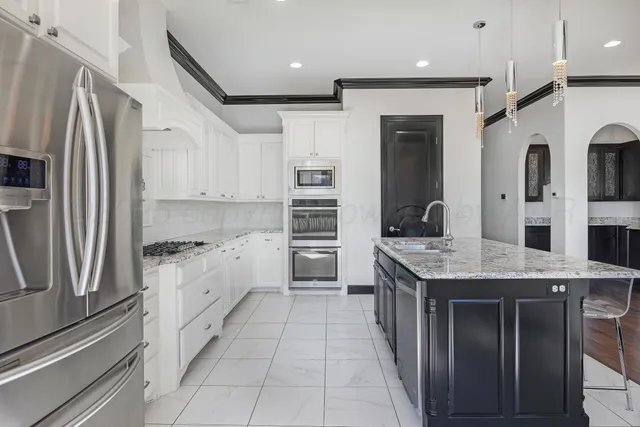 a kitchen with stainless steel appliances granite countertop a kitchen island a stove a sink and a refrigerator