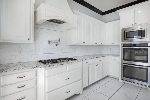 a kitchen with granite countertop white cabinets and stainless steel appliances