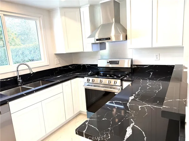 a kitchen with granite countertop a sink a stove and cabinets