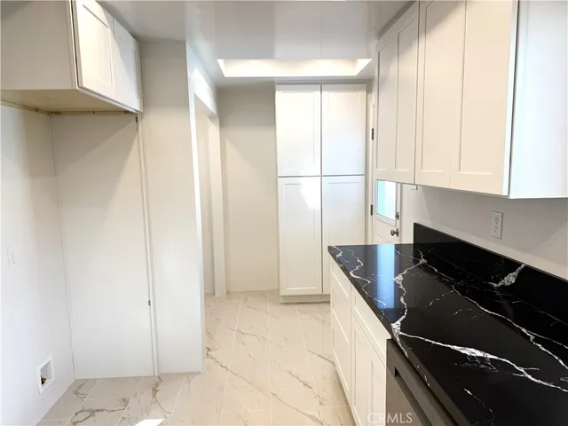 a kitchen with granite countertop white cabinets and black appliances