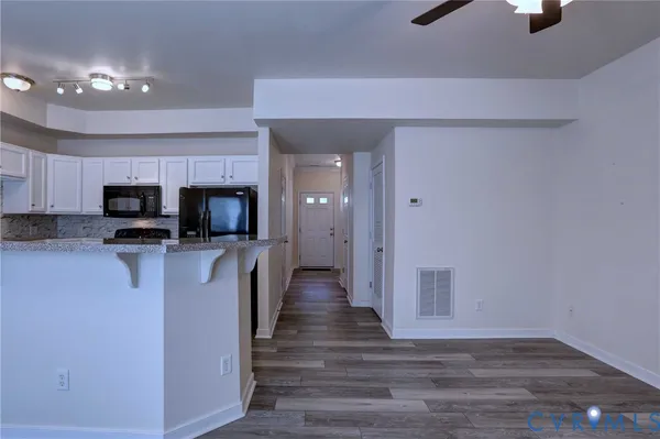 a view of a kitchen with stainless steel appliances wooden floor and chair