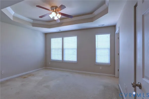 an empty room with chandelier fan and windows