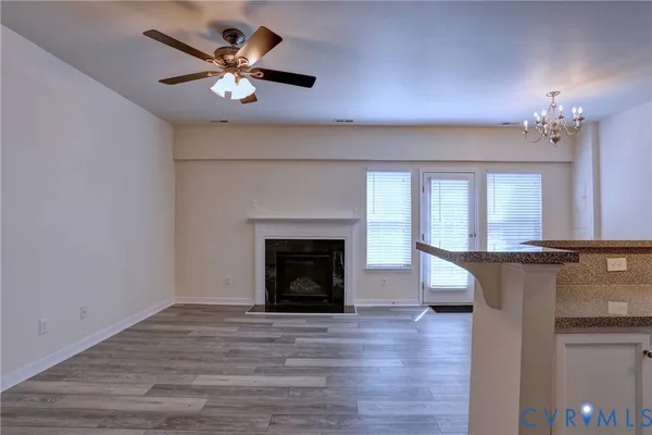 a view of a livingroom with a fireplace a ceiling fan and wooden floor