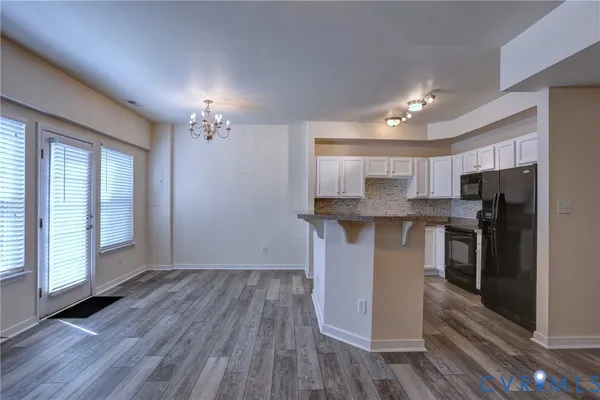 a kitchen with stainless steel appliances granite countertop a refrigerator a sink and a stove with wooden floors