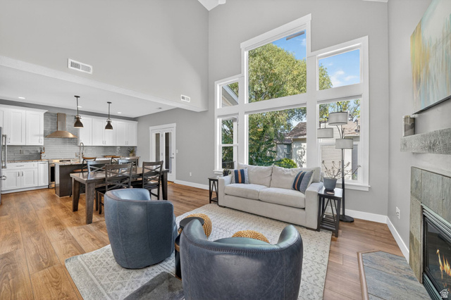 7872 Farm House Lane Midvale, UT 84047 - Photo 5 of 39 Vaulted ceiling with extensive window array, wood-finish flooring, built-in fireplace with hearth, recessed lighting, and kitchen island with pendant lighting