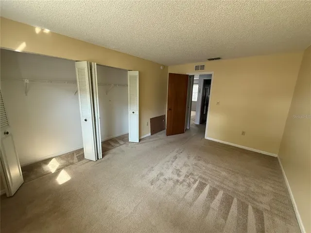 a view of an empty room with closet and wooden floor