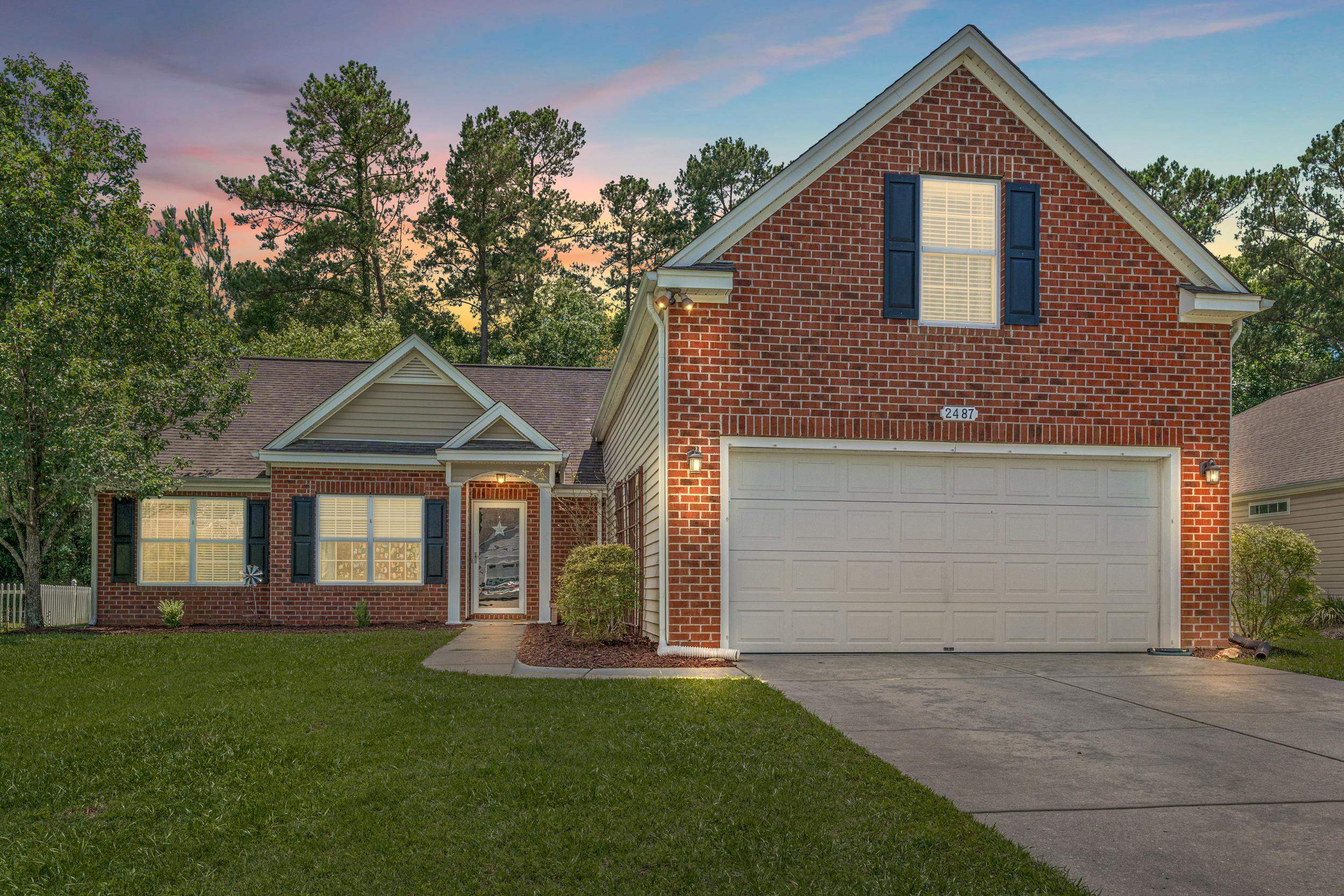 View of front of home featuring brick siding, a yard, and driveway