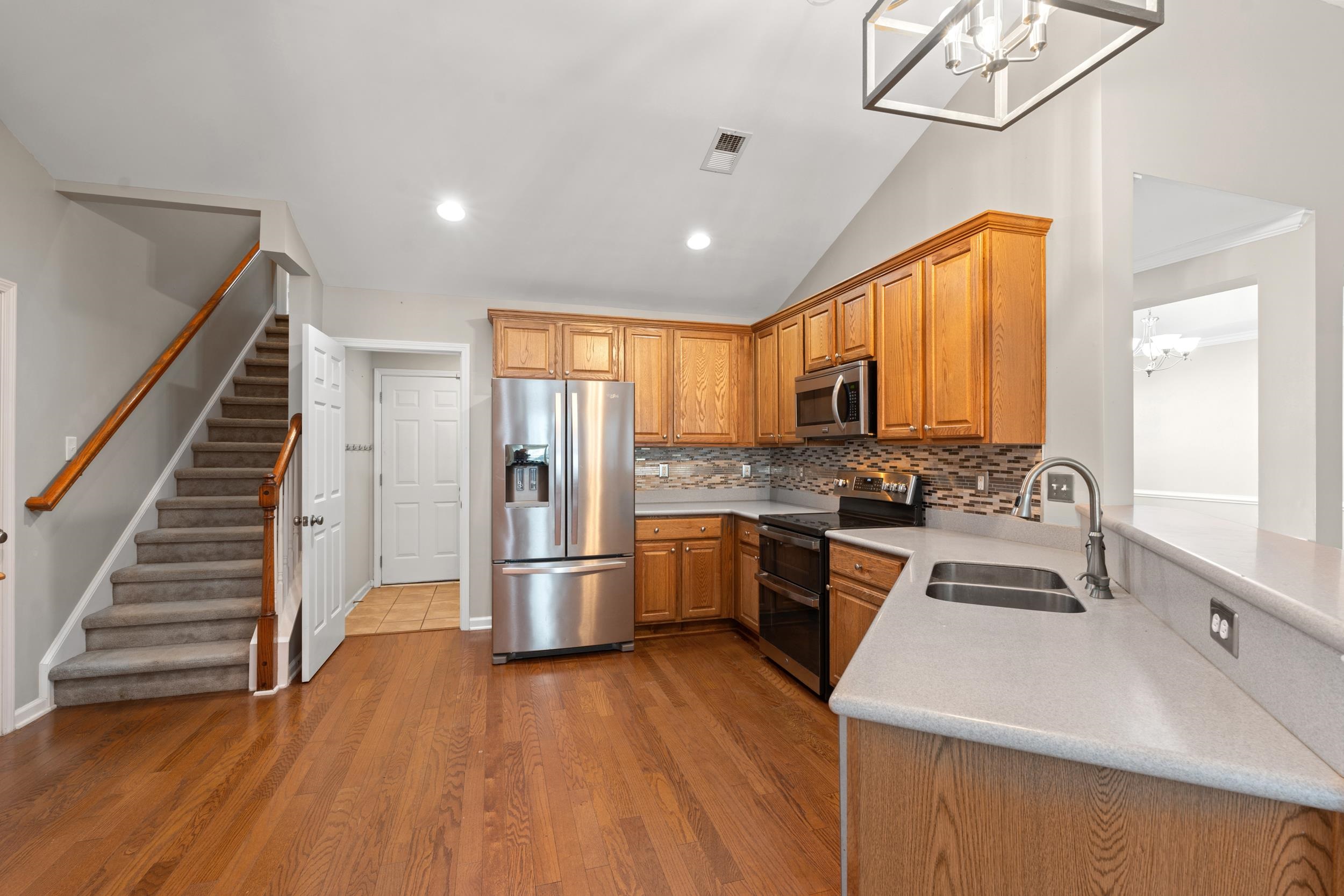 2487 Windmill Way Myrtle Beach, SC 29579 - Photo 17 of 40 Kitchen featuring a chandelier, stainless steel appliances, backsplash, dark wood-type flooring, and brown cabinetry