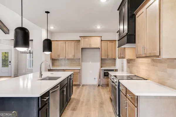 a view of kitchen with granite countertop a sink stainless steel appliances and a chandelier