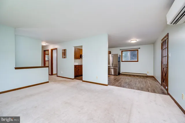 an empty room with windows and refrigerator