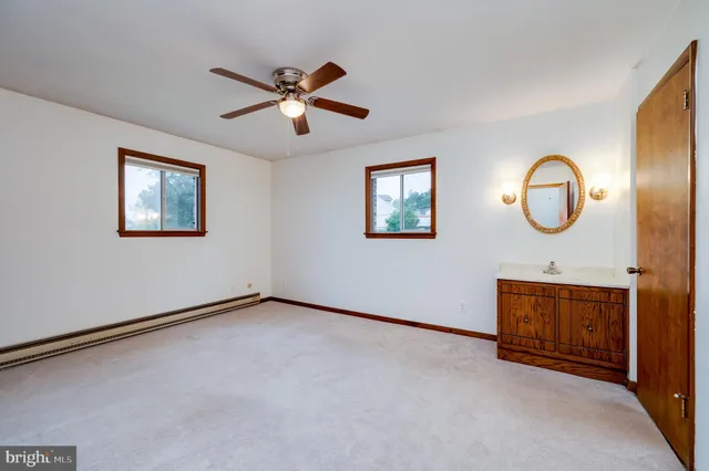 an empty room with windows and fan
